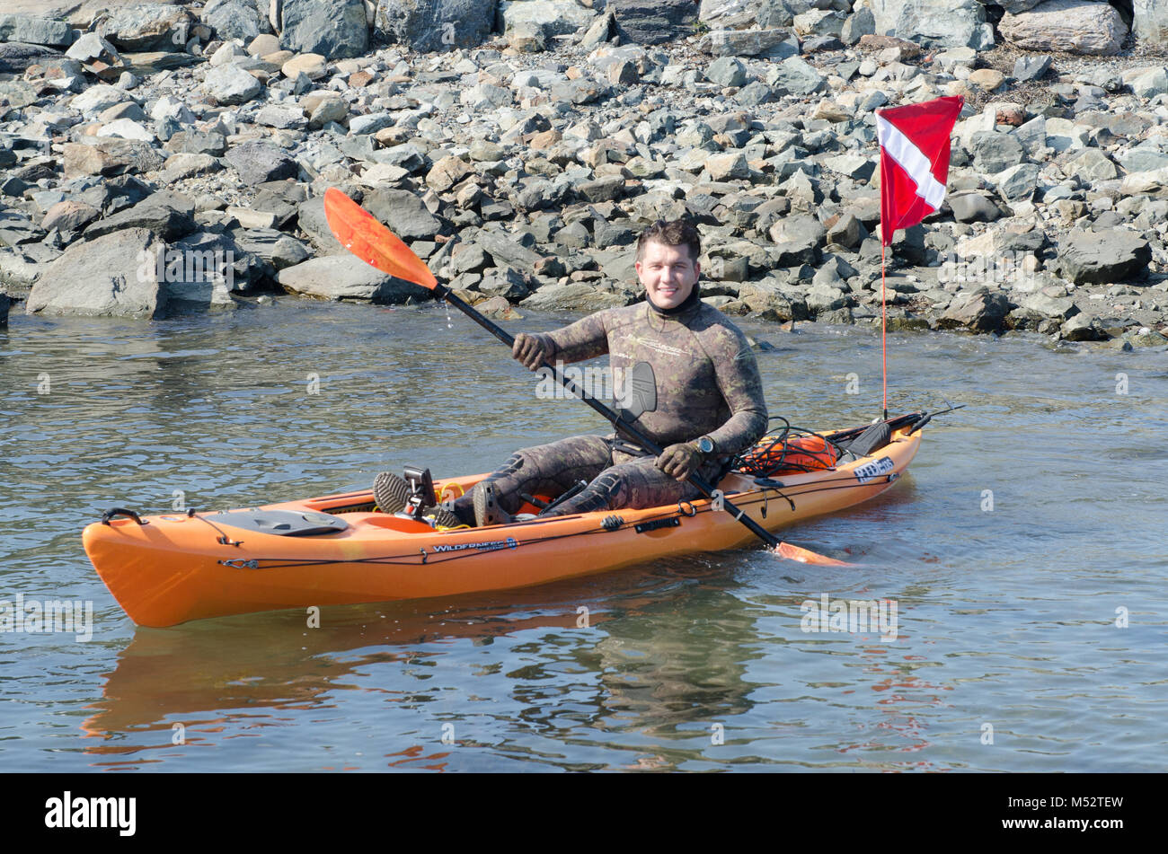 Spear fisherman sets out on kayak to go lobster diving along Newport RI coast. Stock Photo