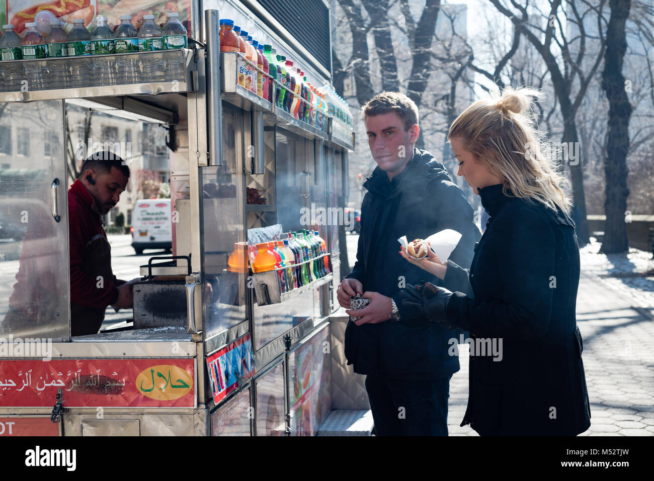 Young blonde couple gets a hot dog in Central Park while on vacation in New York City. Stock Photo