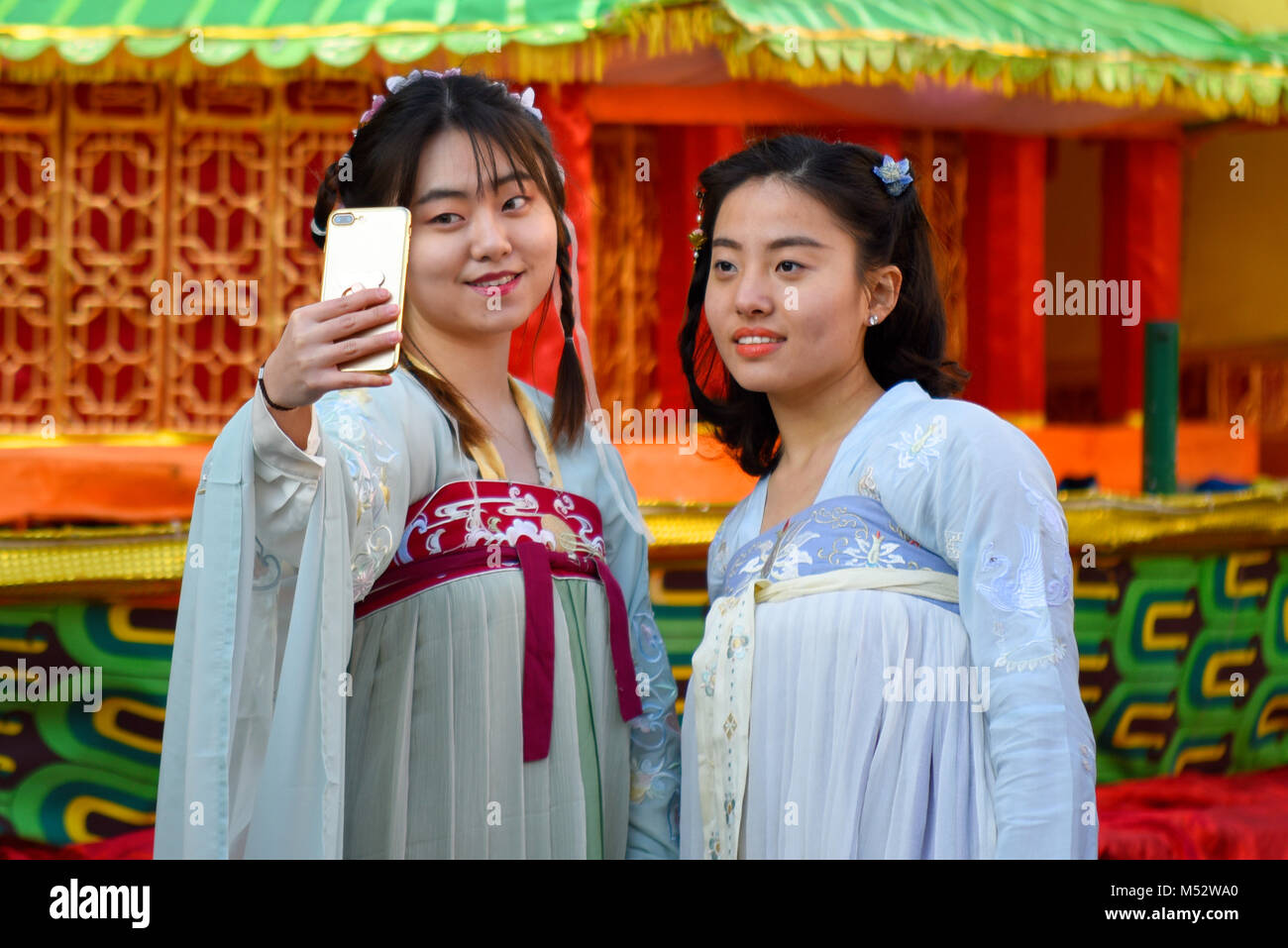 Two traditionally dressed Chinese girls taking a selfie during the Chinese New Year parade celebrations in London. Stock Photo