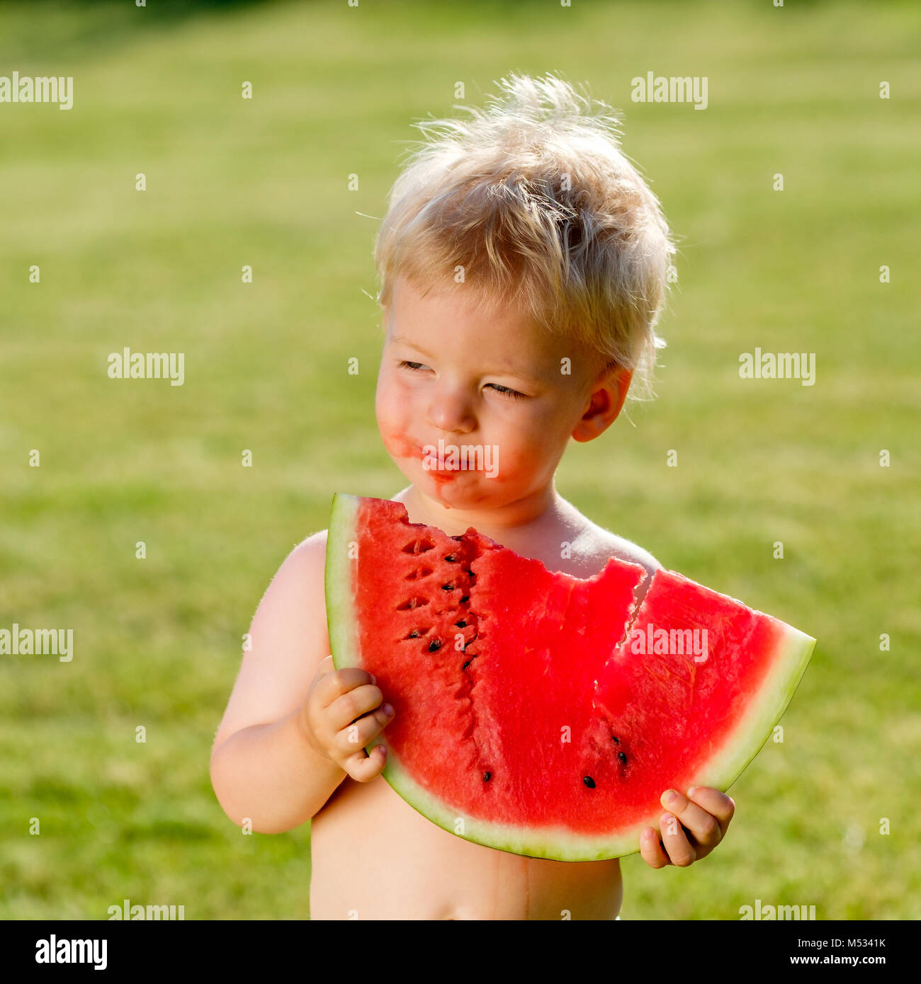 One year old baby boy eating watermelon in the garden Stock Photo