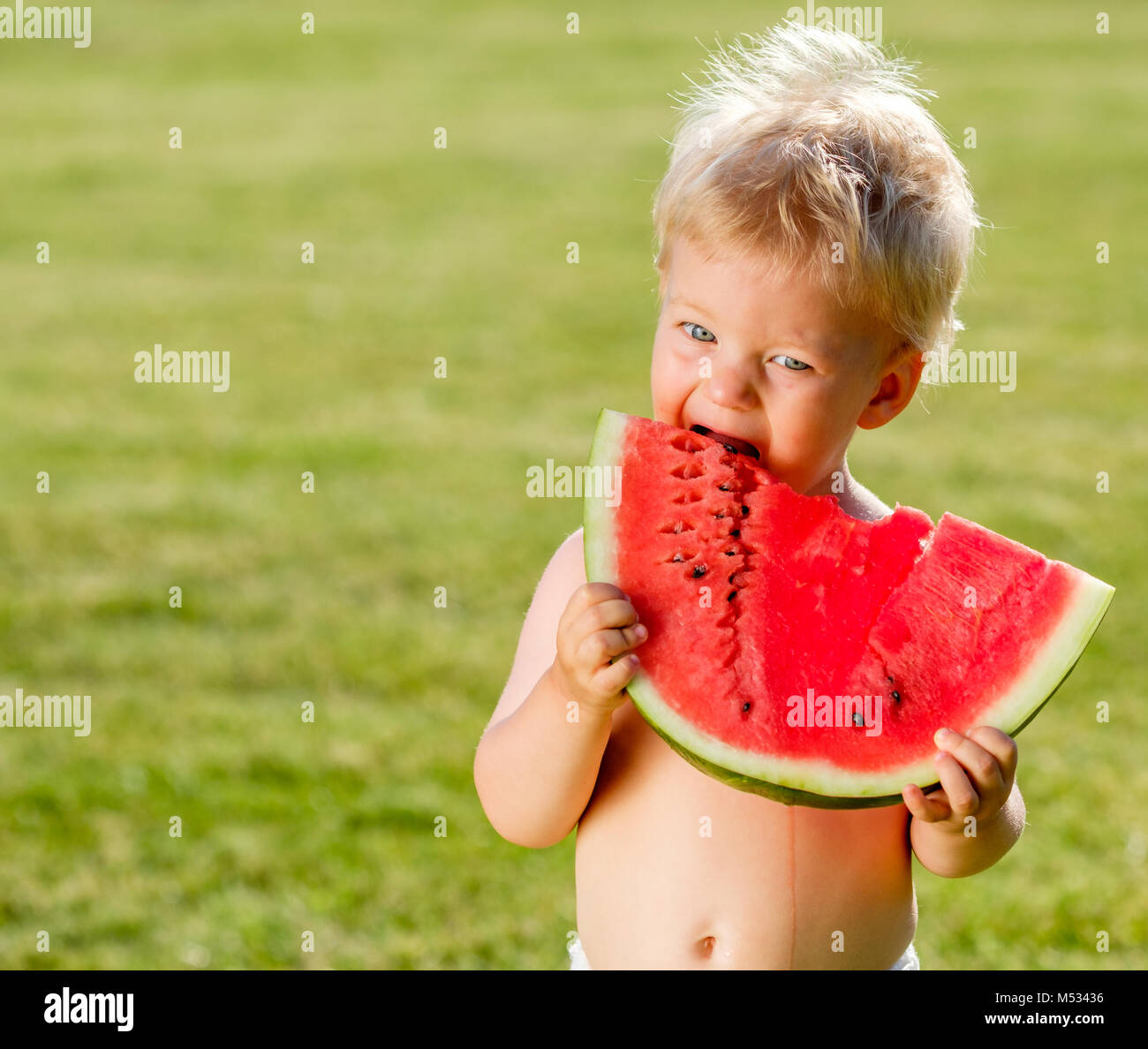 One year old baby boy eating watermelon in the garden Stock Photo