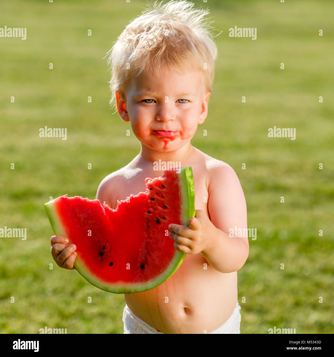 One year old baby boy eating watermelon in the garden Stock Photo