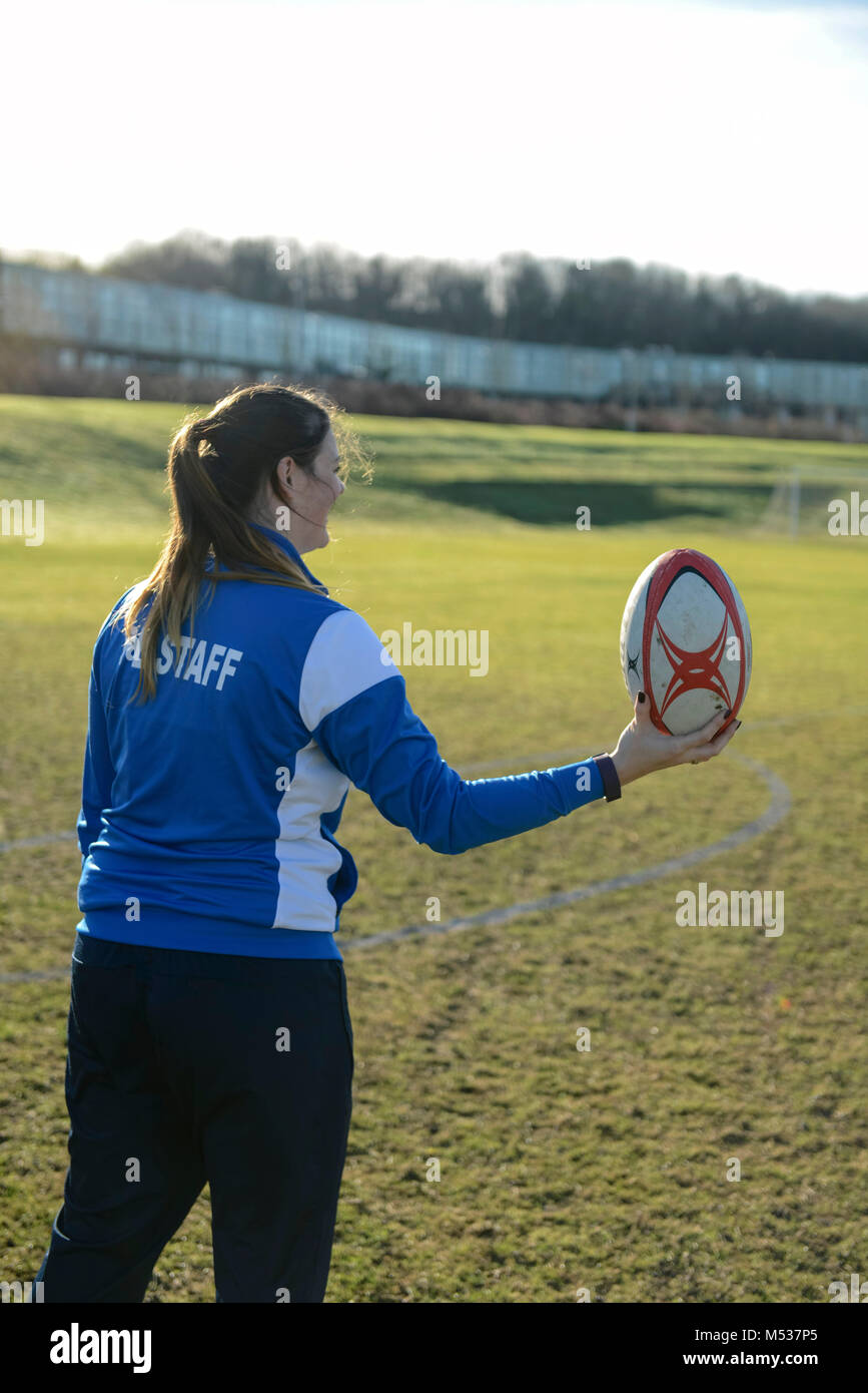 A school PE lesson where the teacher is teaching the college students rugby and throwing and catching the ball on a school sports pitch Stock Photo