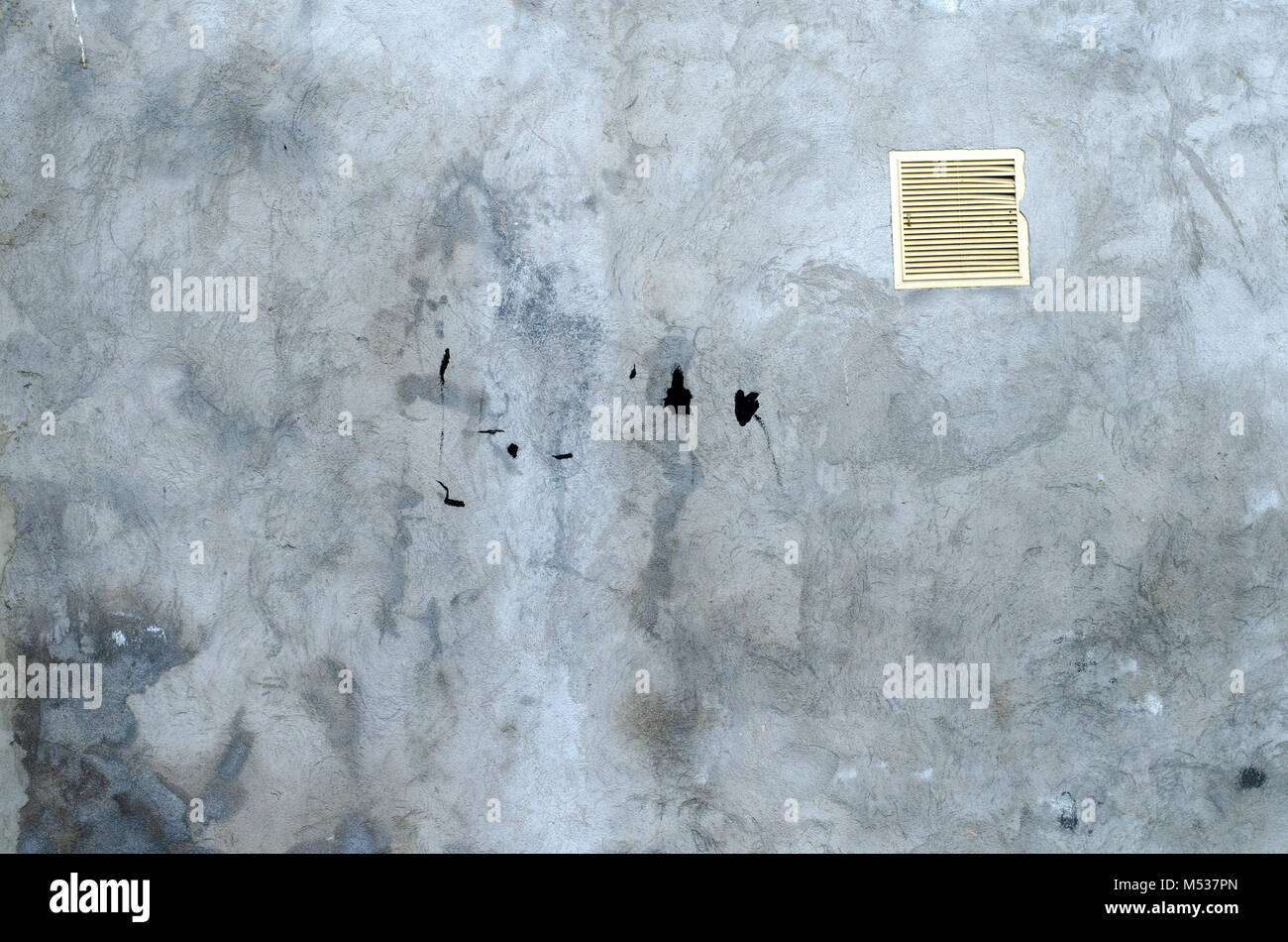 old grey concrete garage wall with spots of black paint with white