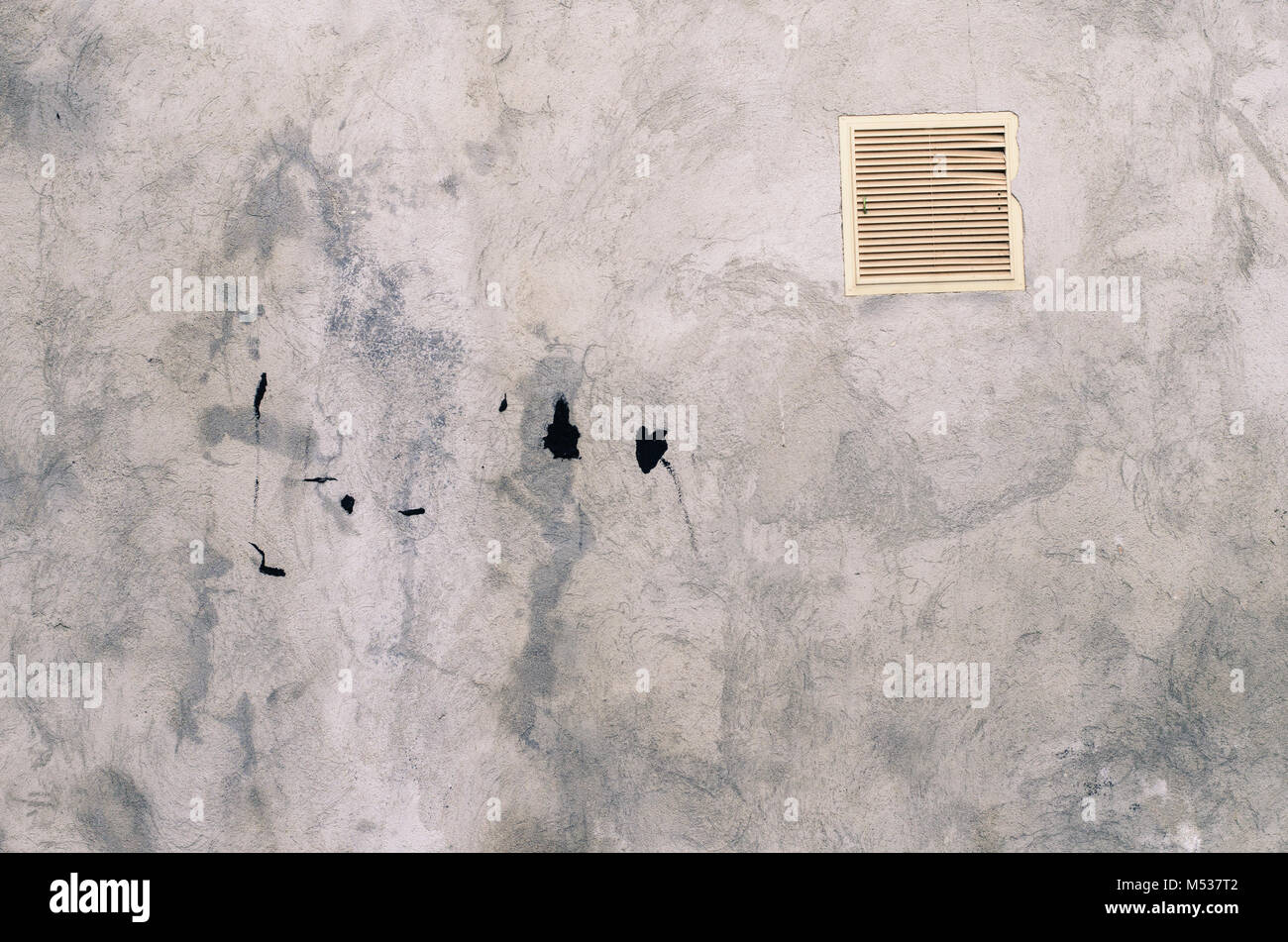 old grey concrete garage wall with spots of black paint with white