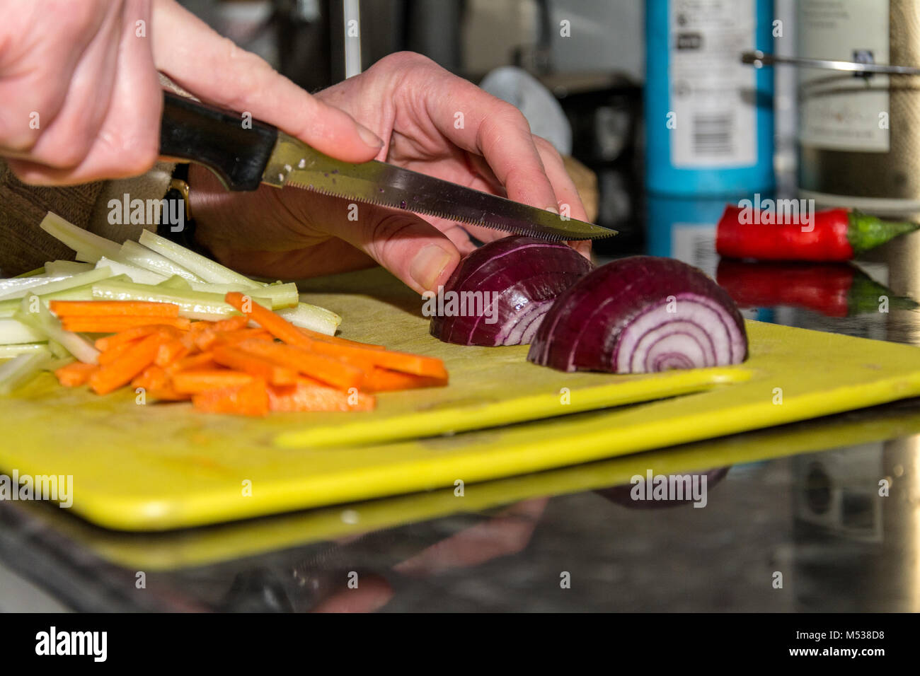 Authentic and candid shot of woman chopping red onion next to batons of