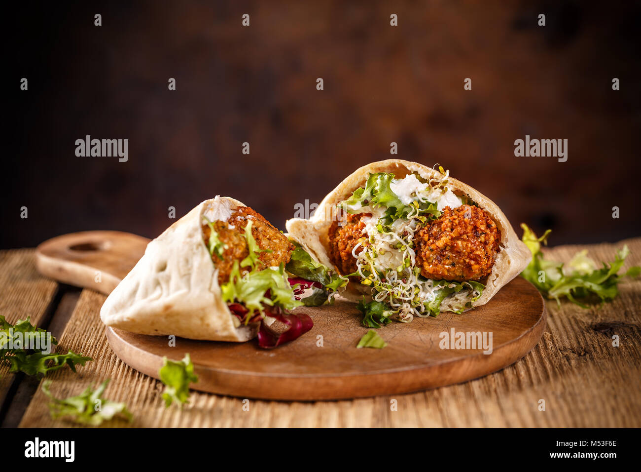 Falafel and fresh lettuce in pita bread on wooden table Stock Photo