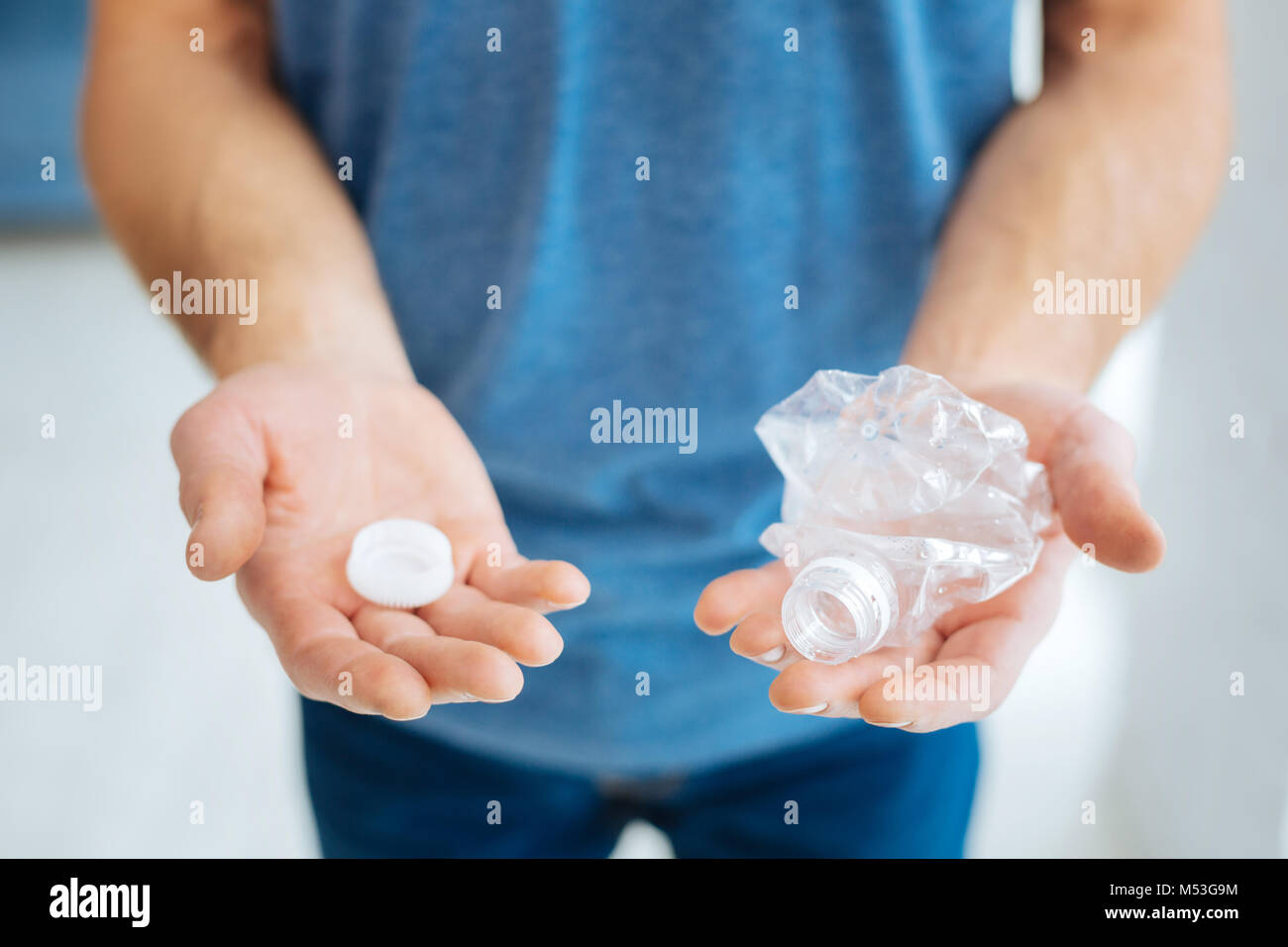 Male hands holding a crushed plastic bottle Stock Photo