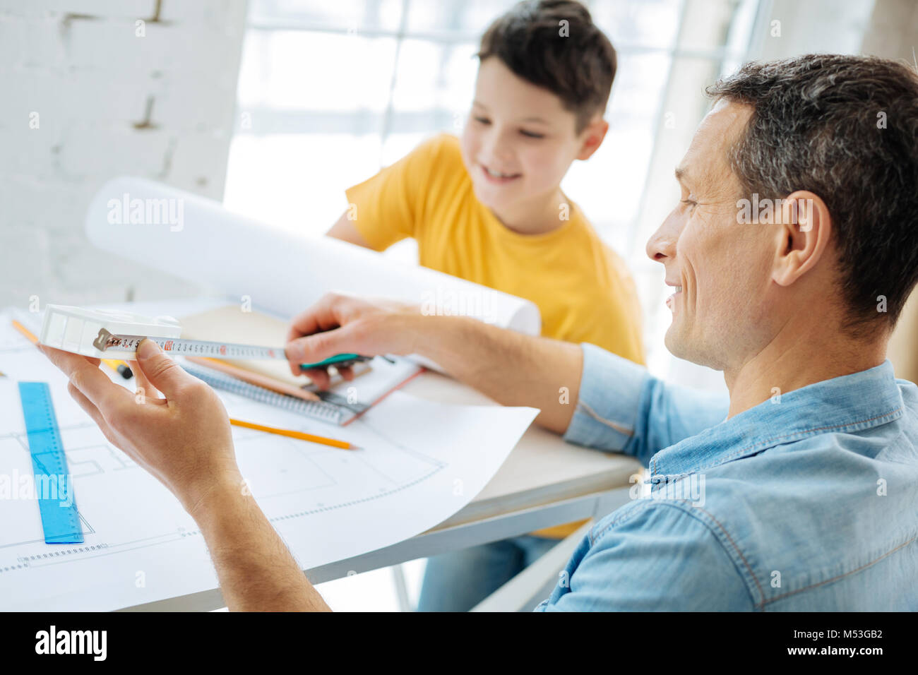 Pleasant man measuring distances on blueprint Stock Photo