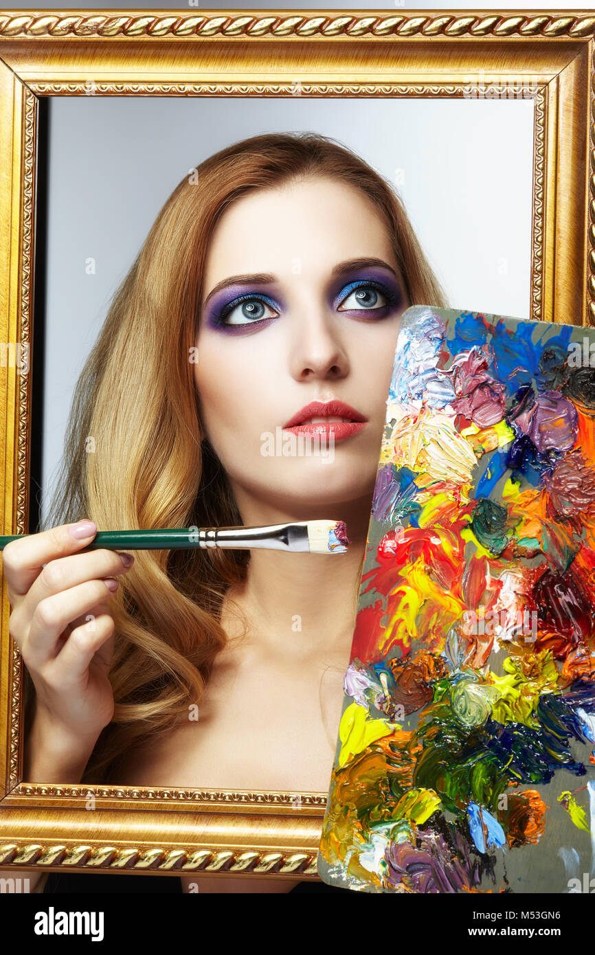 Young woman painter in golden frame with color palette and paint brush ...