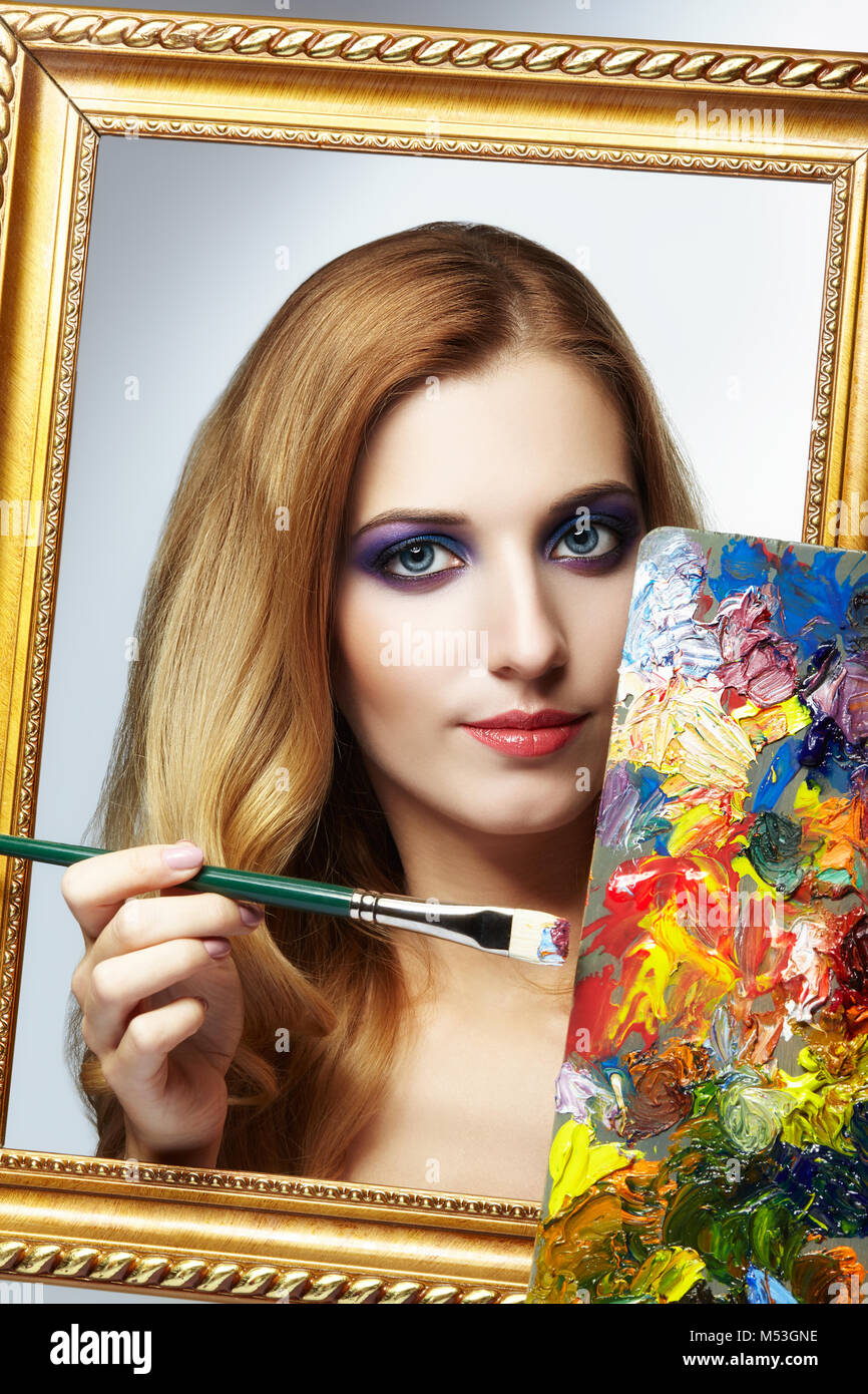 Young woman painter in golden frame with color palette and paint brush ...