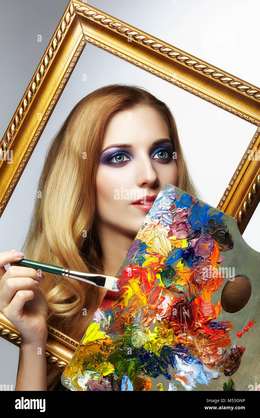 Young woman painter in golden frame with color palette and paint brush ...