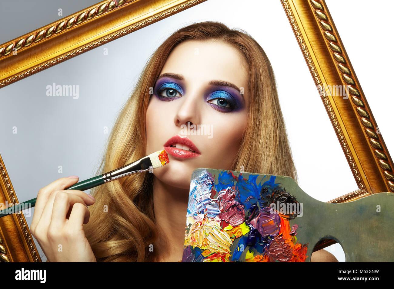 Young woman painter in golden frame with color palette and paint brush ...