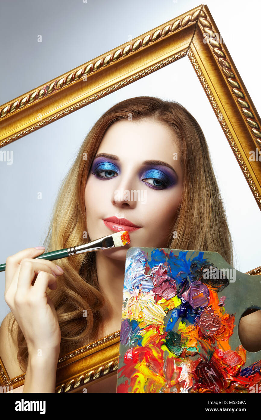 Young woman painter in golden frame with color palette and paint brush ...
