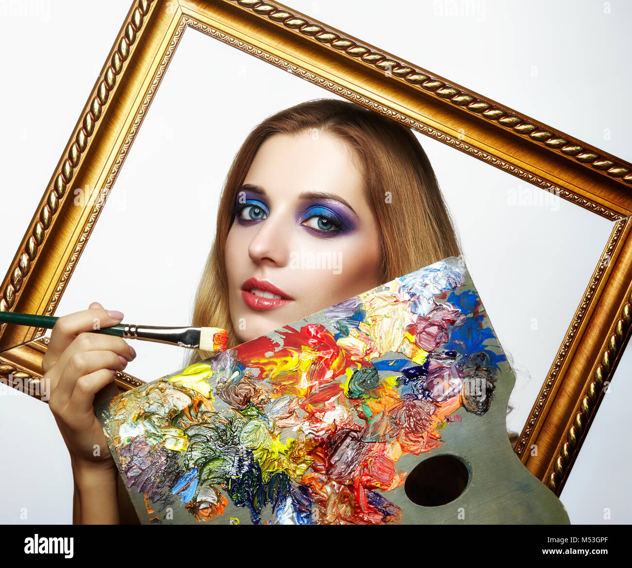 Young woman painter in golden frame with color palette and paint brush ...