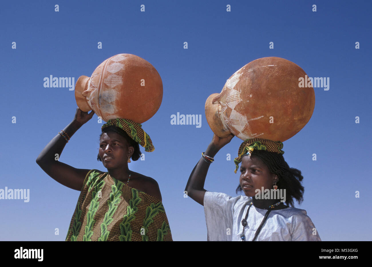 Mali. Anderamboukane, near Menaka. Sahara desert. Sahel. People of Bella tribe (former slaves of Tuareg). Women carrying pot on head. Stock Photo