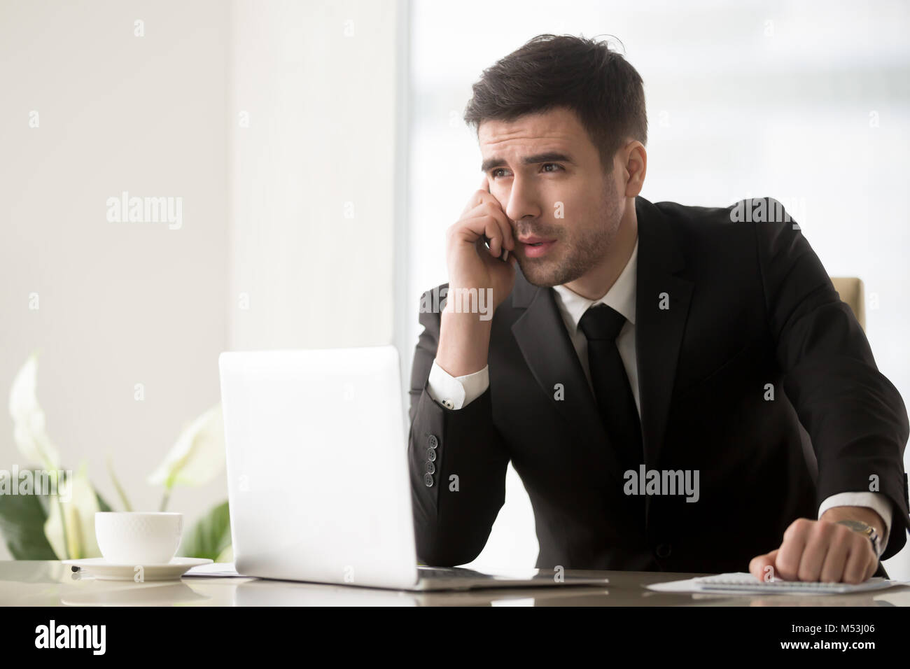 Businessman answering phone call at desk in office Stock Photo