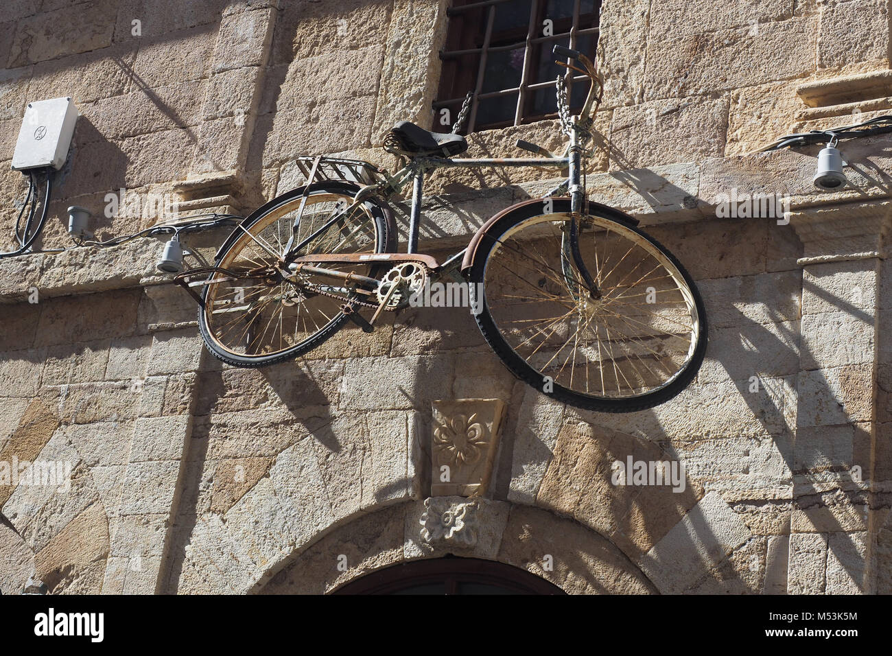 Old rusty bicycle hangs on a wall Kavala, Macedonia, Greece Stock Photo