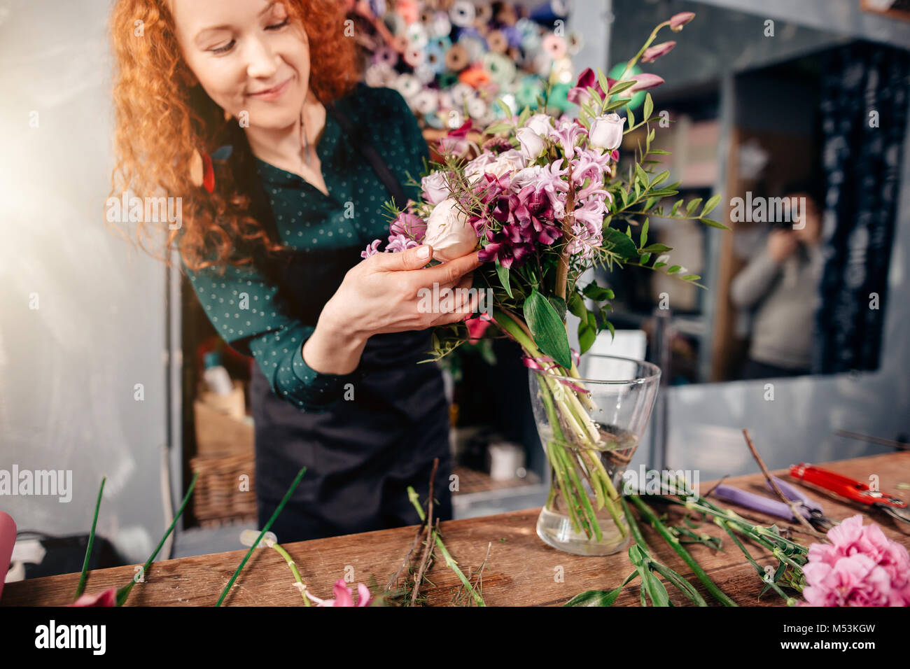 female putting winsome flowers in vase in florist's shop Stock Photo
