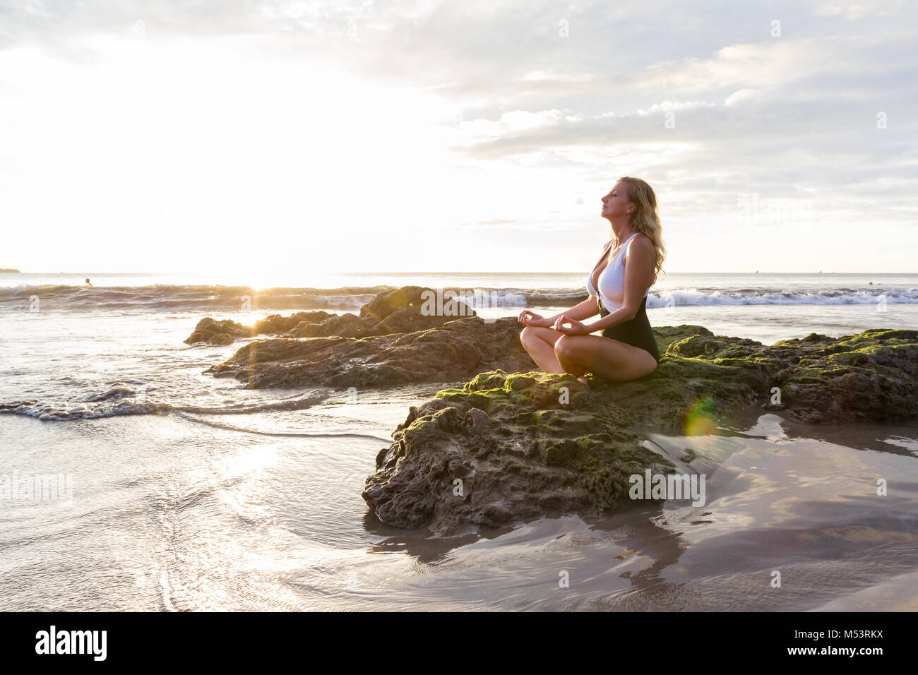 attractive woman meditating finding her inner peace on a beautiful afternoon at the beach in Costa Rica Stock Photo