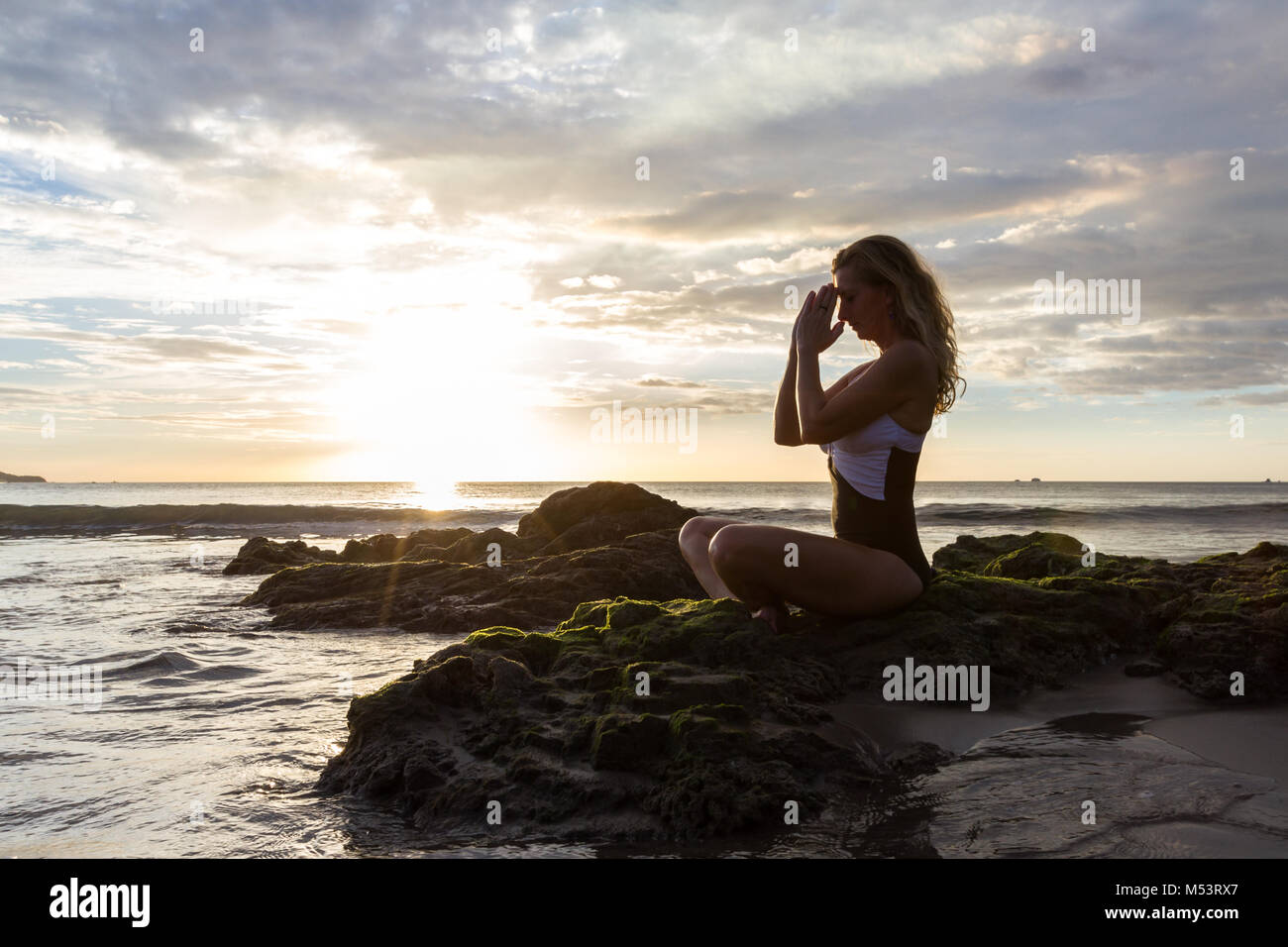 attractive woman meditating finding her inner peace on a beautiful afternoon at the beach in Costa Rica Stock Photo