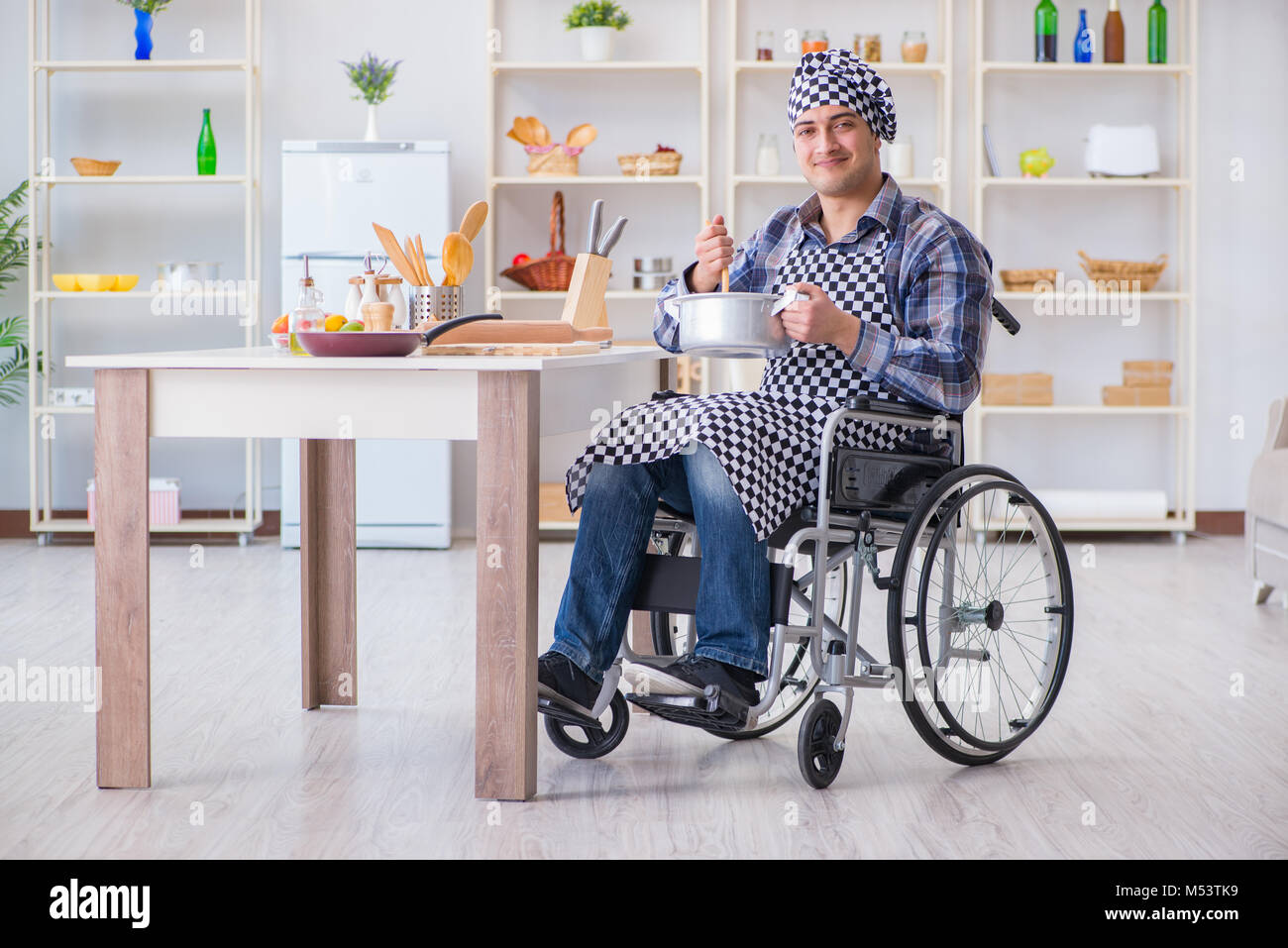 Disabled cook on wheelchair in cooking concept Stock Photo - Alamy