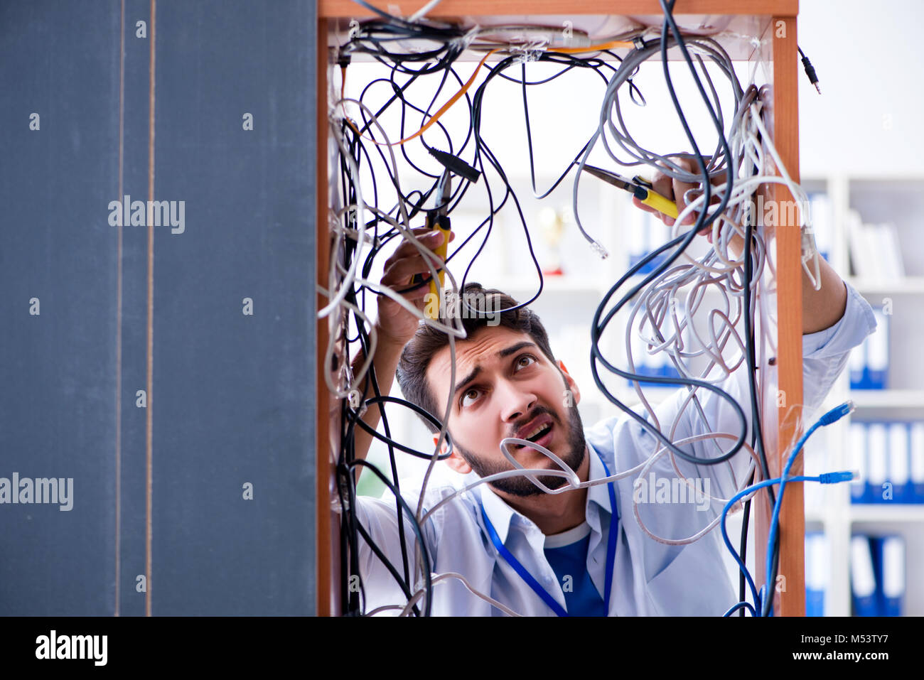 Electrician trying to untangle wires in repair concept Stock Photo - Alamy