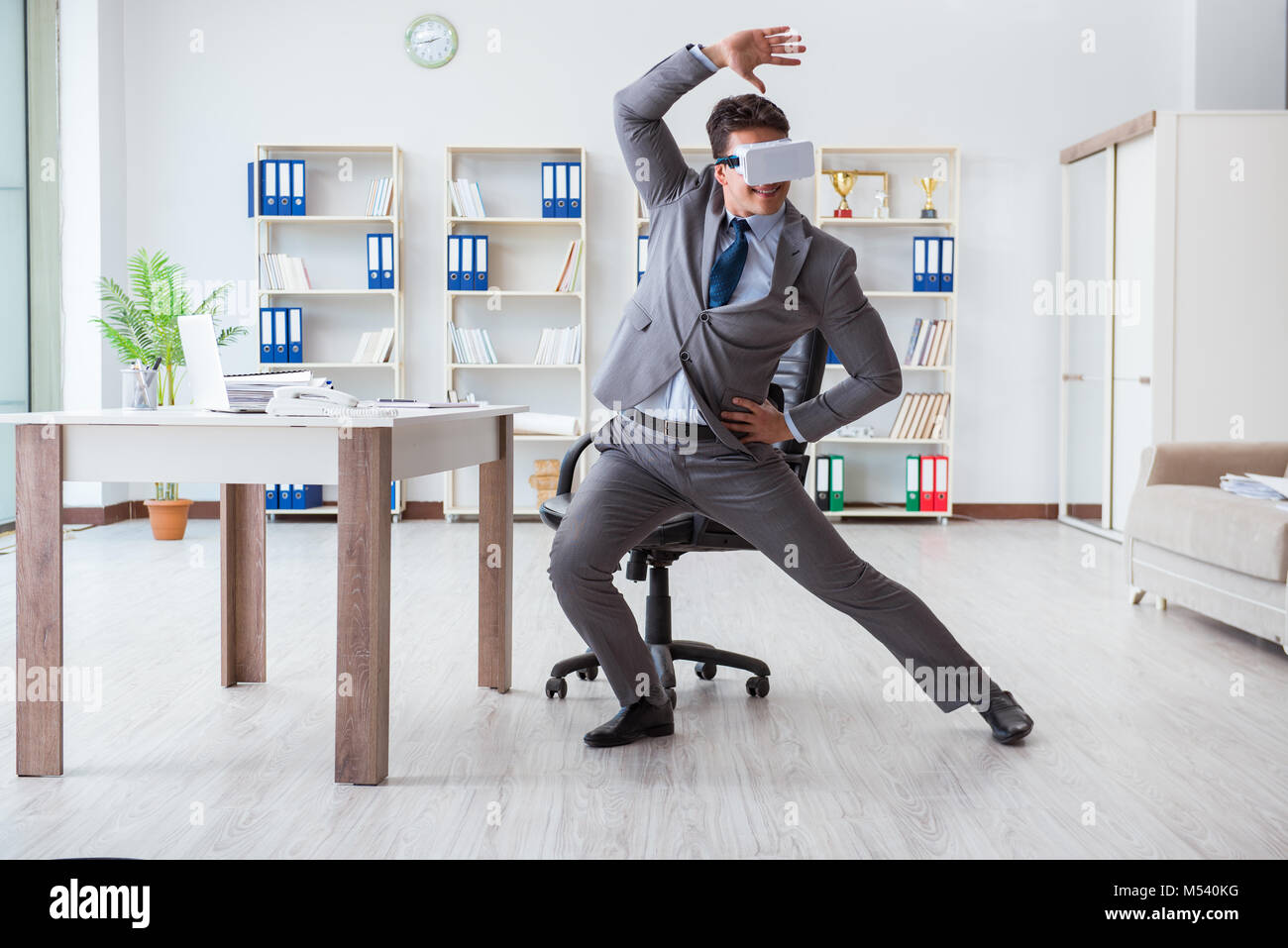 Businessman exercising in office wearing VR glasses Stock Photo - Alamy