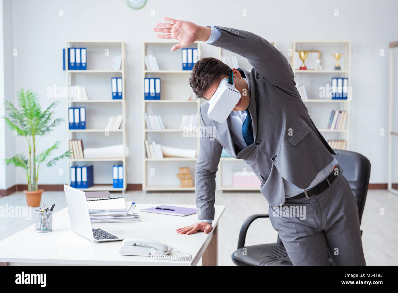 Businessman exercising in office wearing VR glasses Stock Photo - Alamy