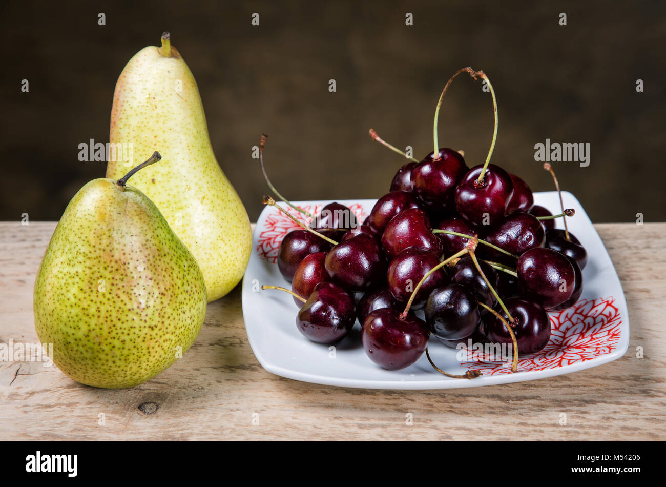 berries cherries in a plate and pears on a table Stock Photo