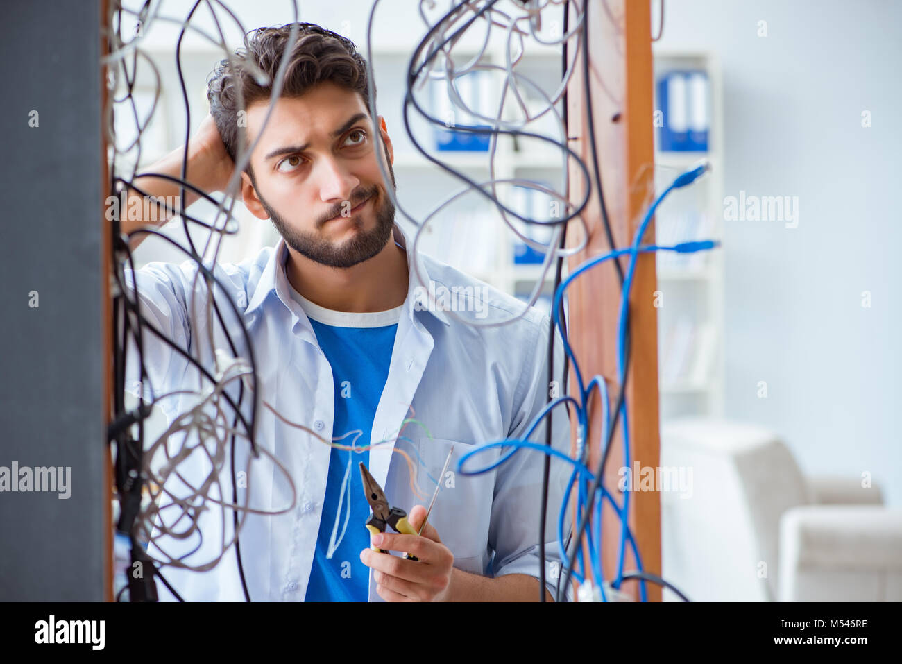 Electrician trying to untangle wires in repair concept Stock Photo Alamy