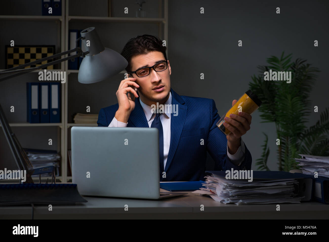 Employee Working Late And Drinking Strong Coffee To Stay Awake