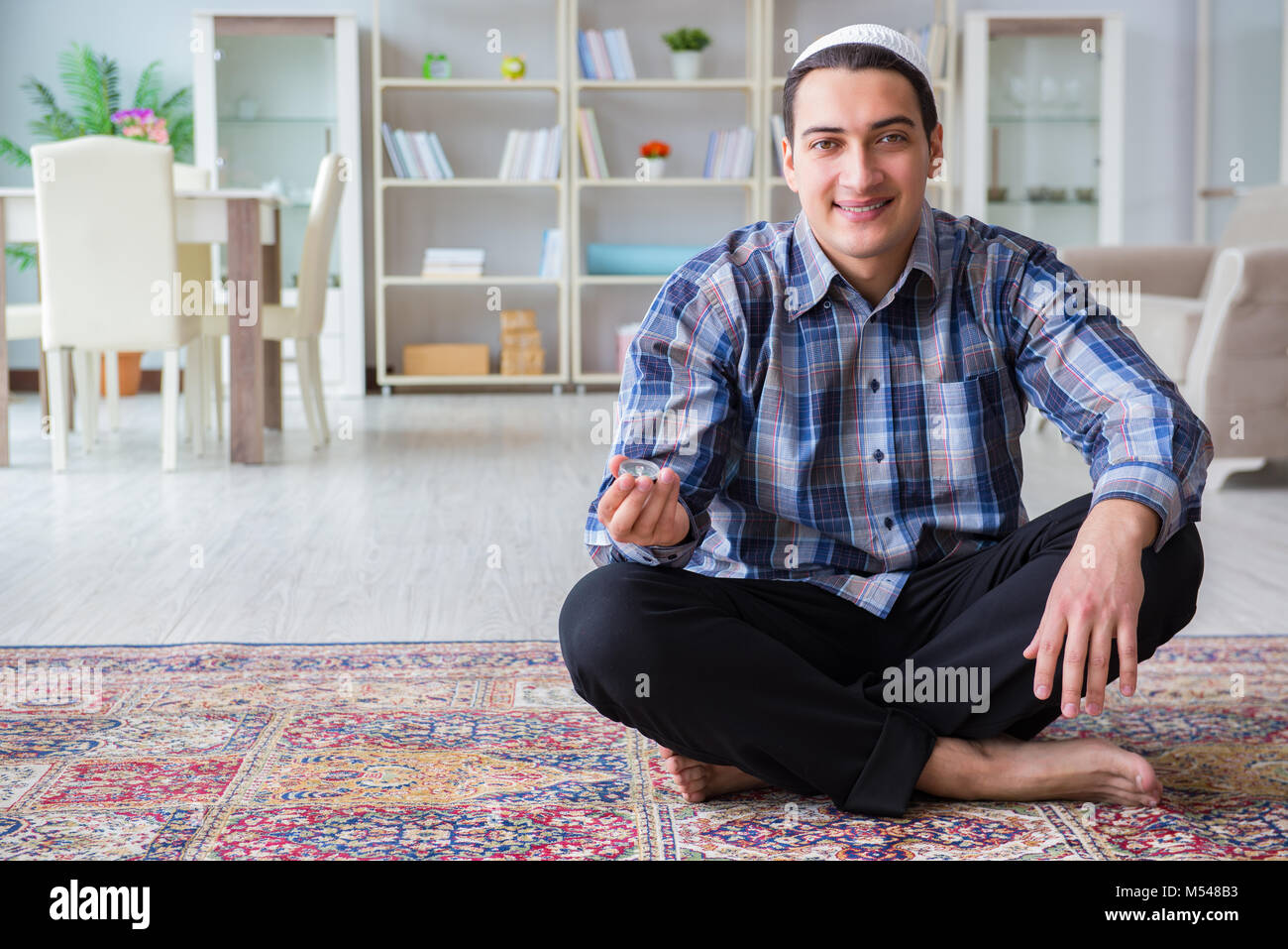 Young muslim man praying at home Stock Photo