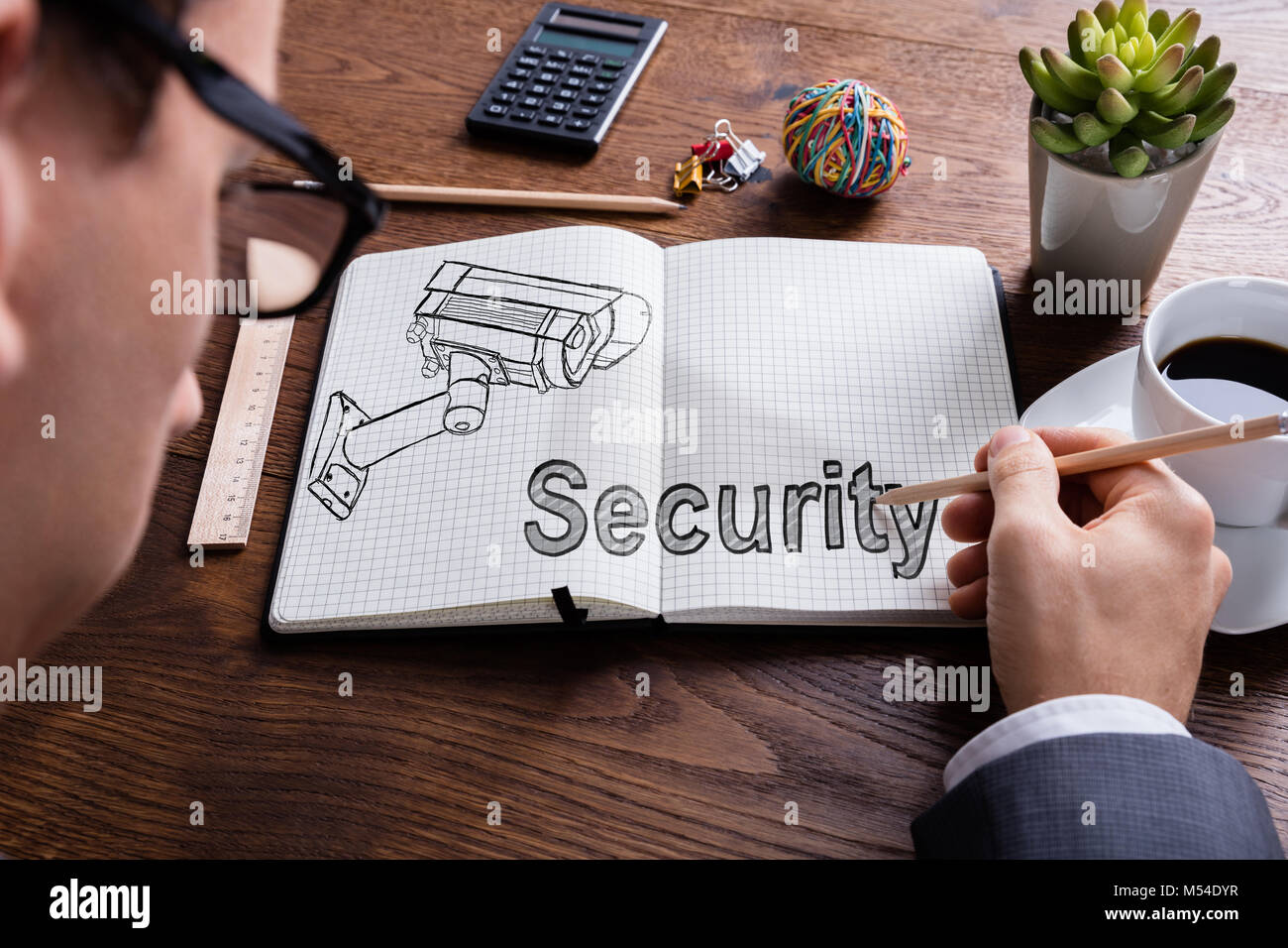 Close-up Of Businessman Drawing Surveillance Camera In Book Stock Photo