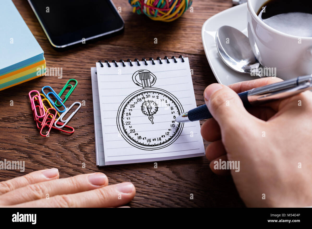 Close-up Of Person Drawing Sketch Of Stopwatch On Notepad Stock Photo