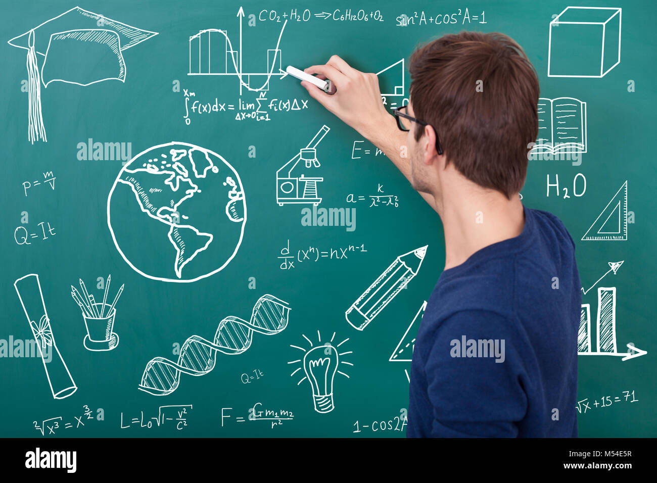 Male Teacher Teaching Physic Equation On Chalkboard In Classroom Stock Photo