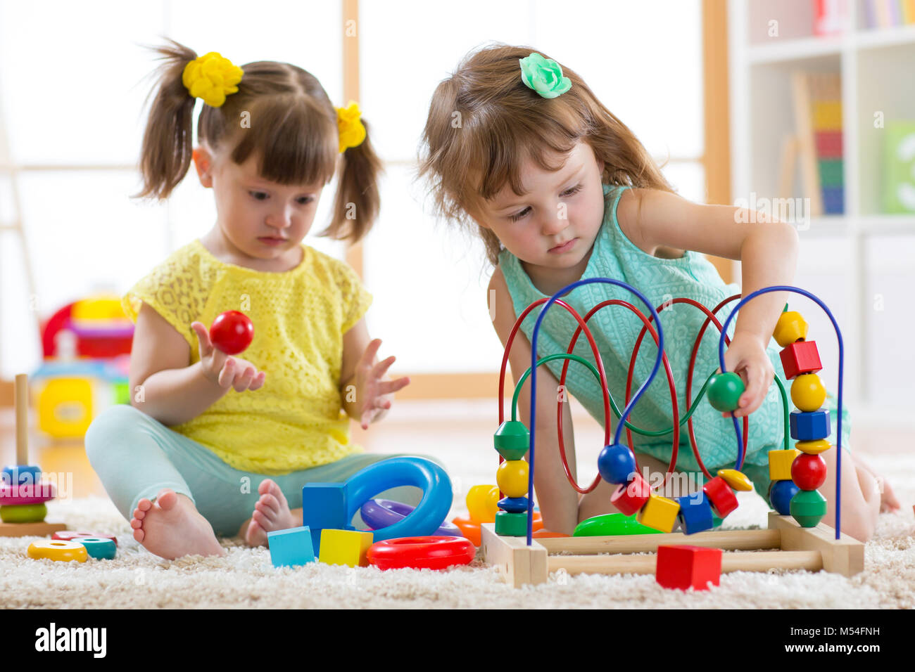 Two kids playing with wooden blocks in their room Stock Photo - Alamy