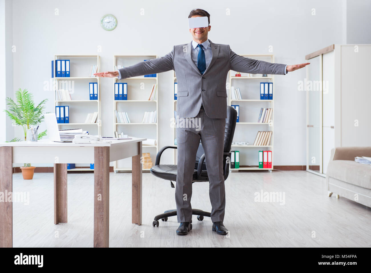 Businessman exercising in office wearing VR glasses Stock Photo - Alamy