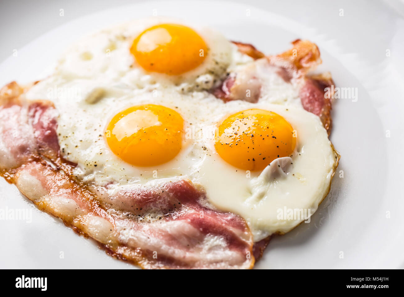 Ham and Eggs. Bacon and Eggs. Salted egg with pepper on white plate