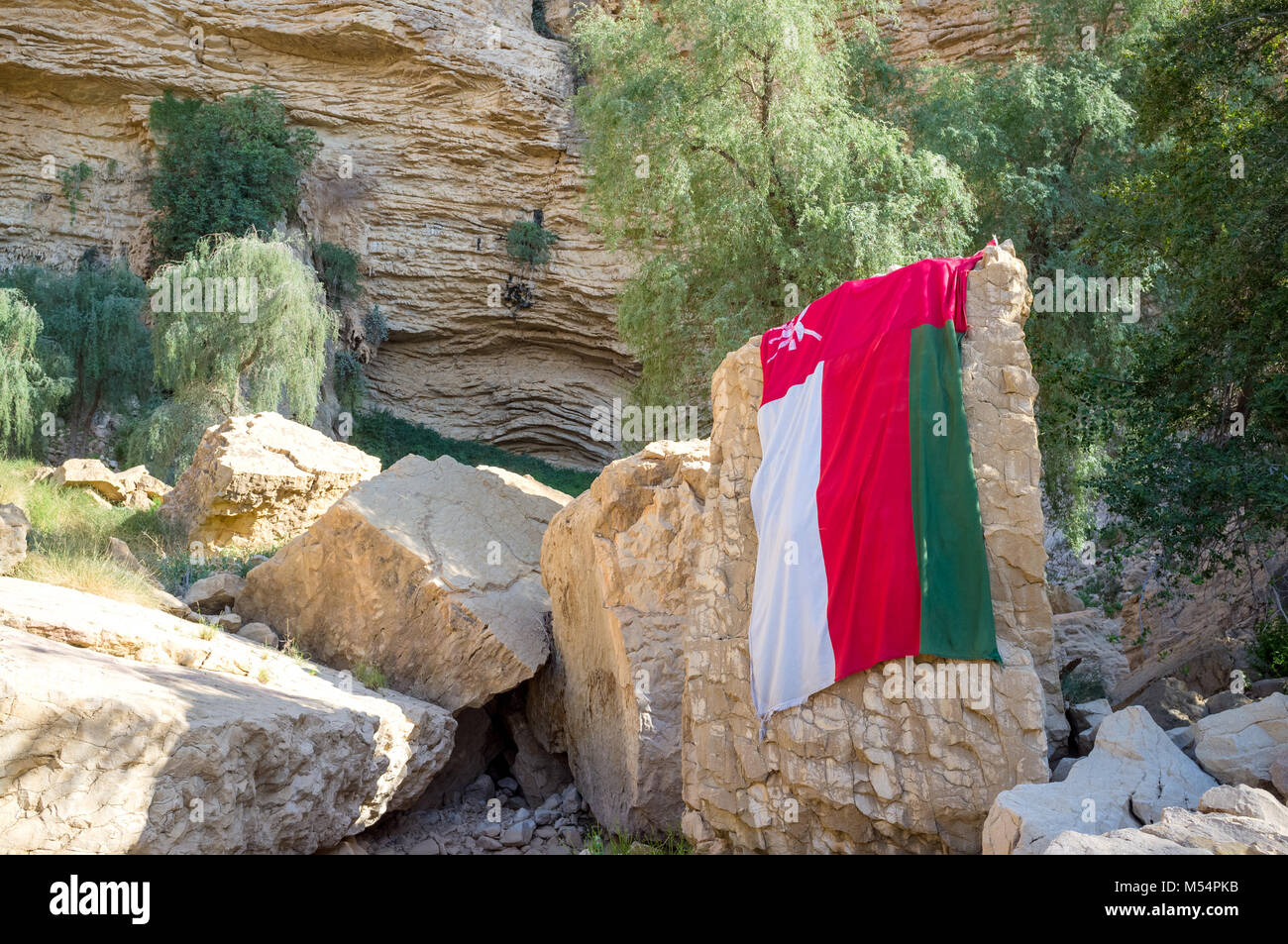 Flag of Oman. Flag is draped on a rock at Jebel Qatar (known as Hanging Gardens) close to Buraimi in Oman on the border with Al Ain and Abu Dhabi Stock Photo