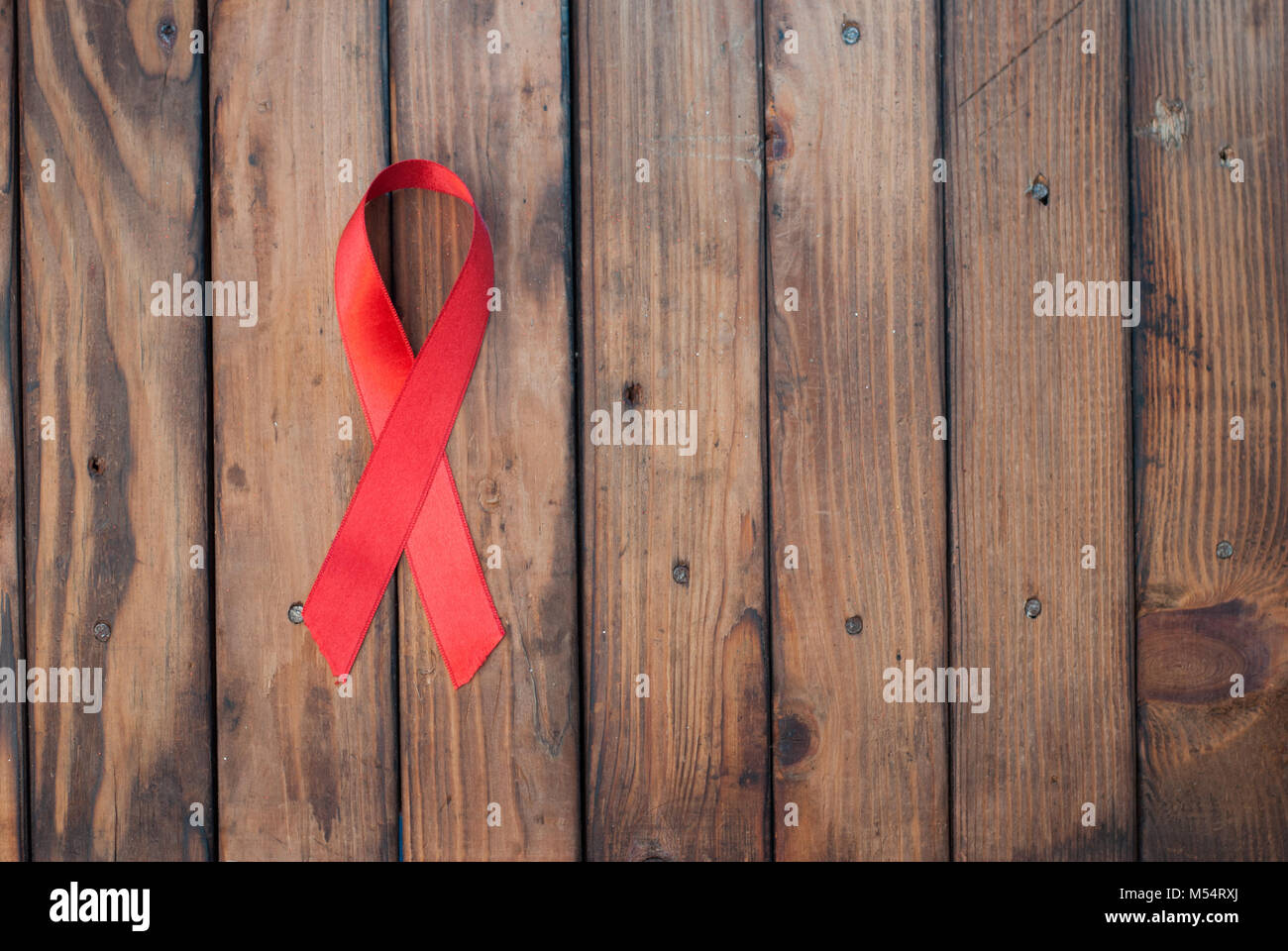 Awareness about world day against AIDS, the red silk ribbon on wooden background Stock Photo