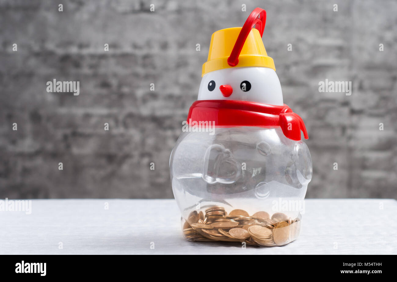 Snowman with coins, transparent piggybank, concept of saving money Stock Photo