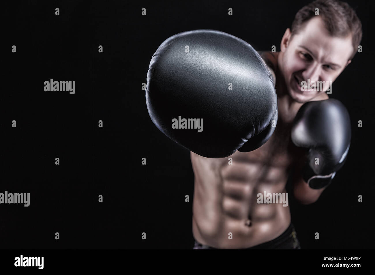 Boxer in boxing gloves directs his hand into the camera on a black ...