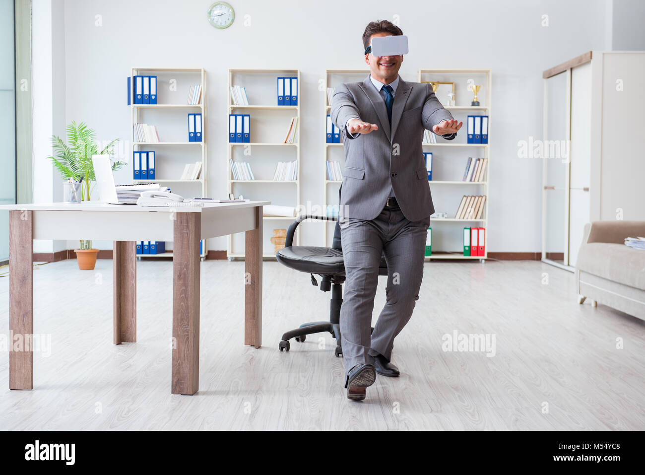The businessman exercising in office wearing vr glasses Stock Photo - Alamy