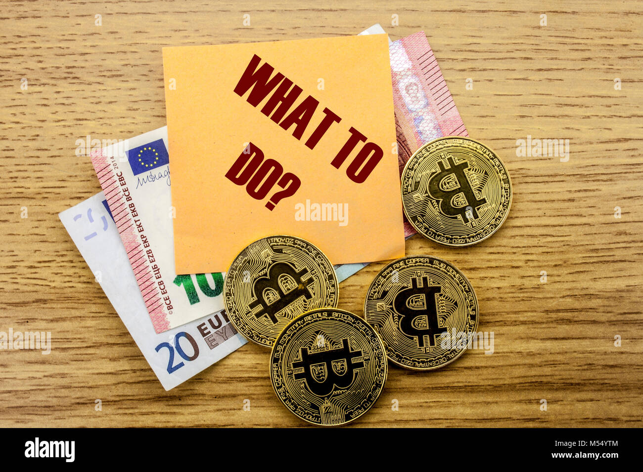 Bitcoins, Bit Coin on Euro, Dollars notes witch sticky note on wooden background, WHAT TO DO bitcoin concept. Stock Photo