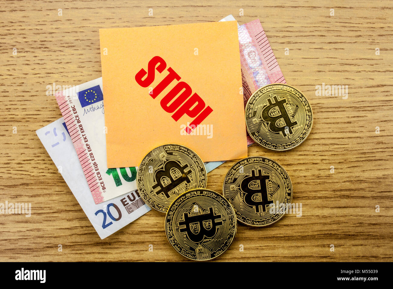 Bitcoins, Bit Coin on Euro, Dollars notes witch sticky note on wooden background, STOP bitcoin concept. Stock Photo