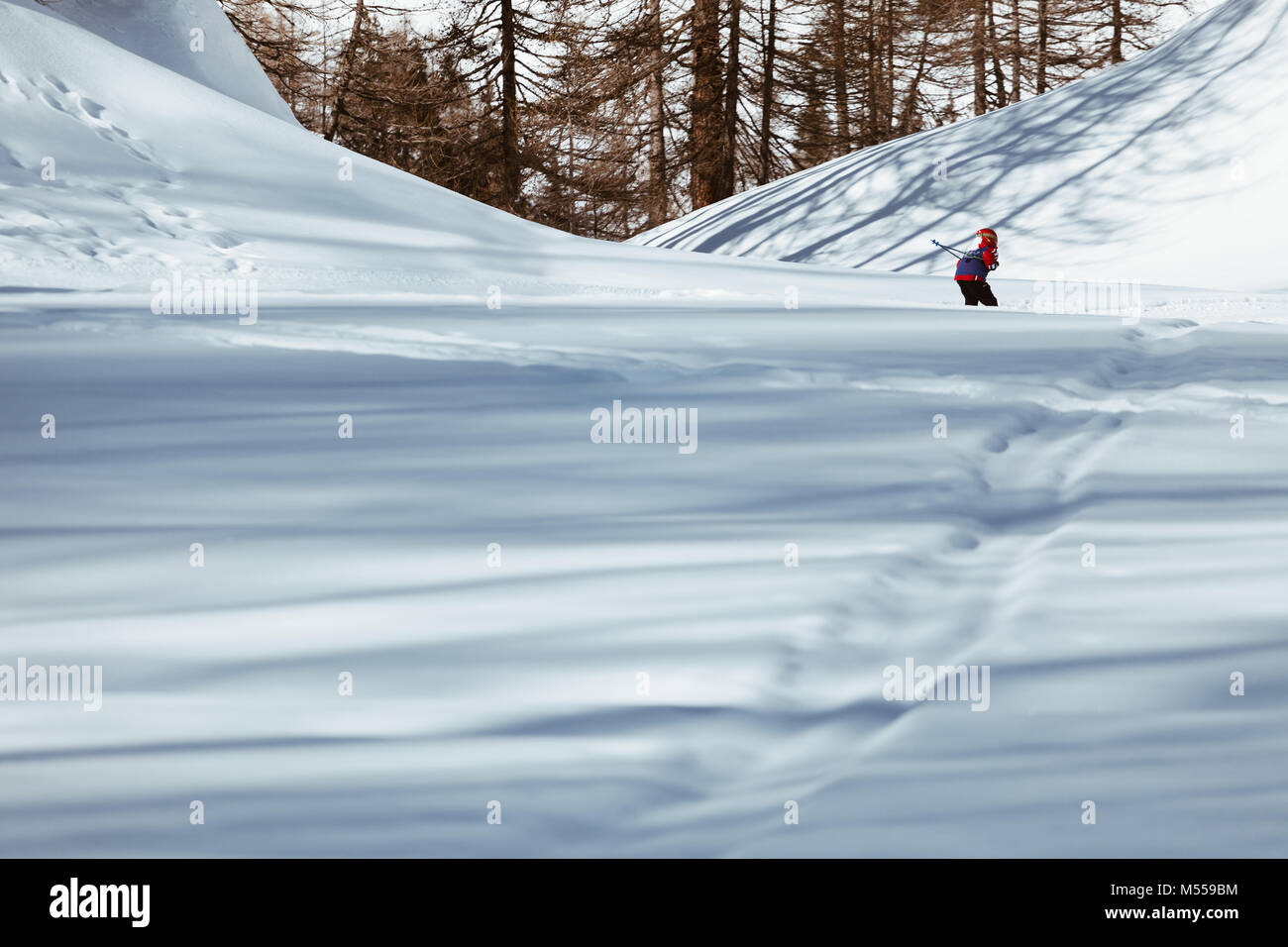 Kid skier skiing down the slope downhill in high mountains Stock