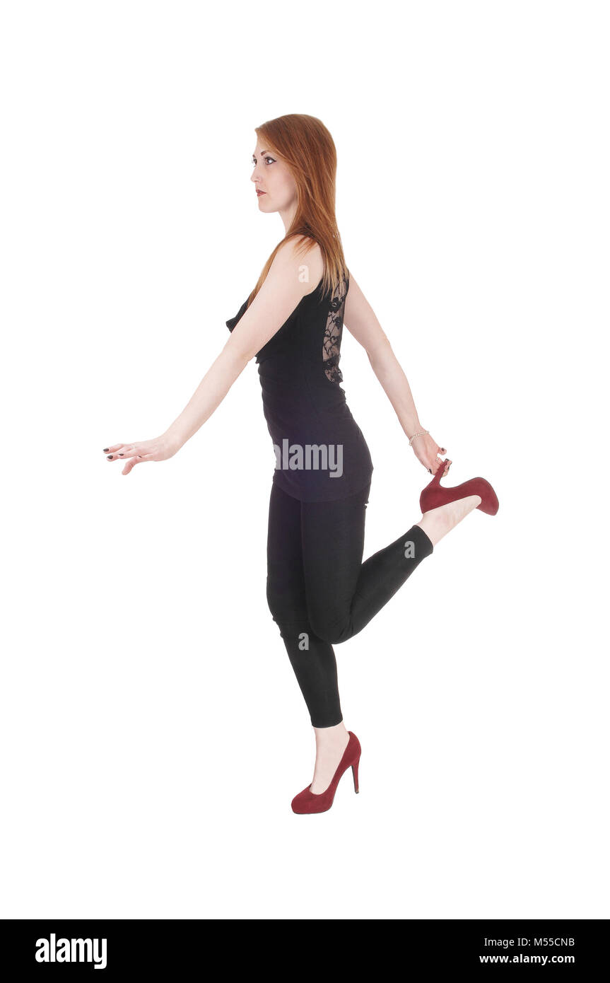 Woman standing on one leg holding heels Stock Photo