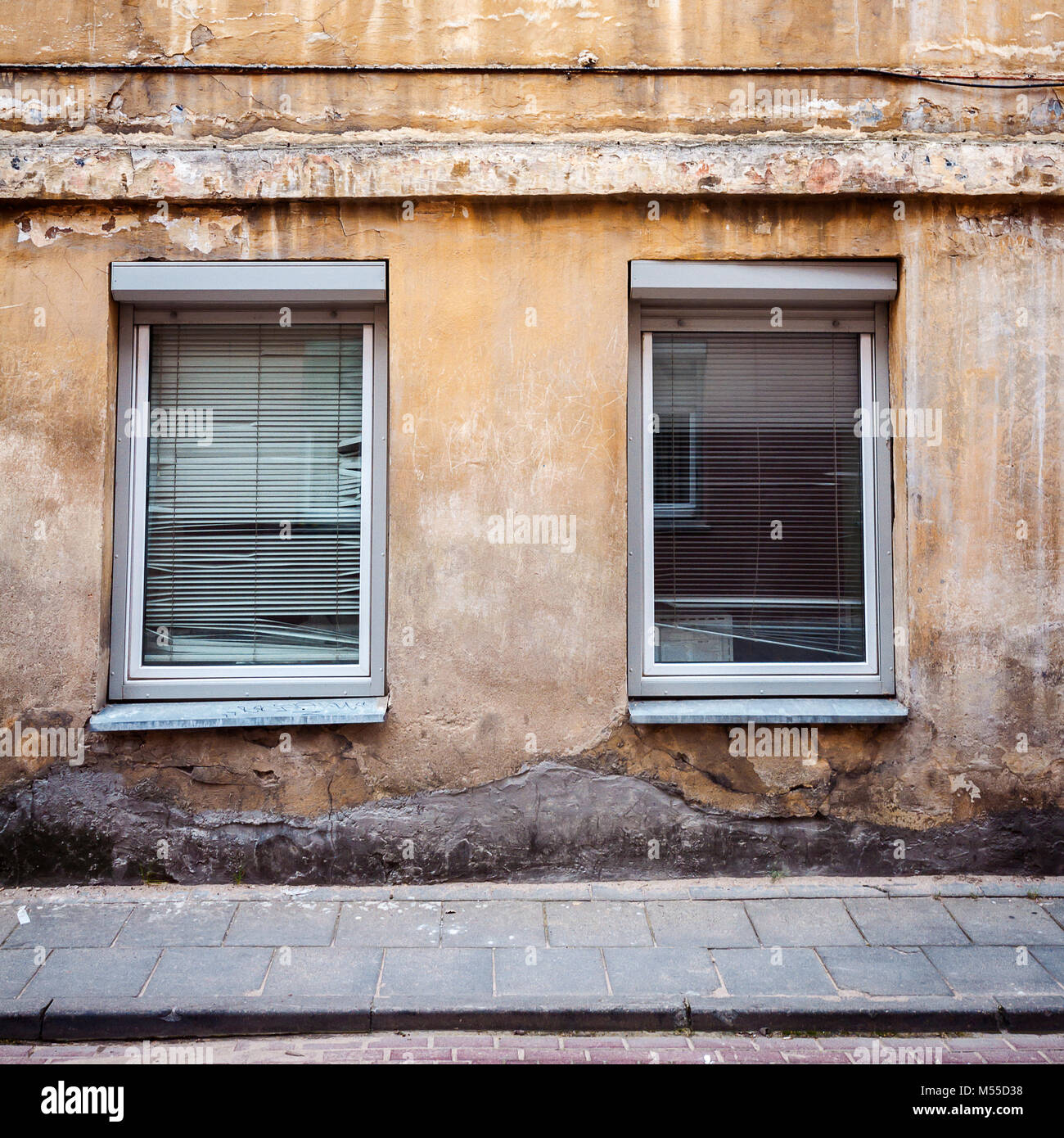 Aged weathered street wall with some windows Stock Photo - Alamy