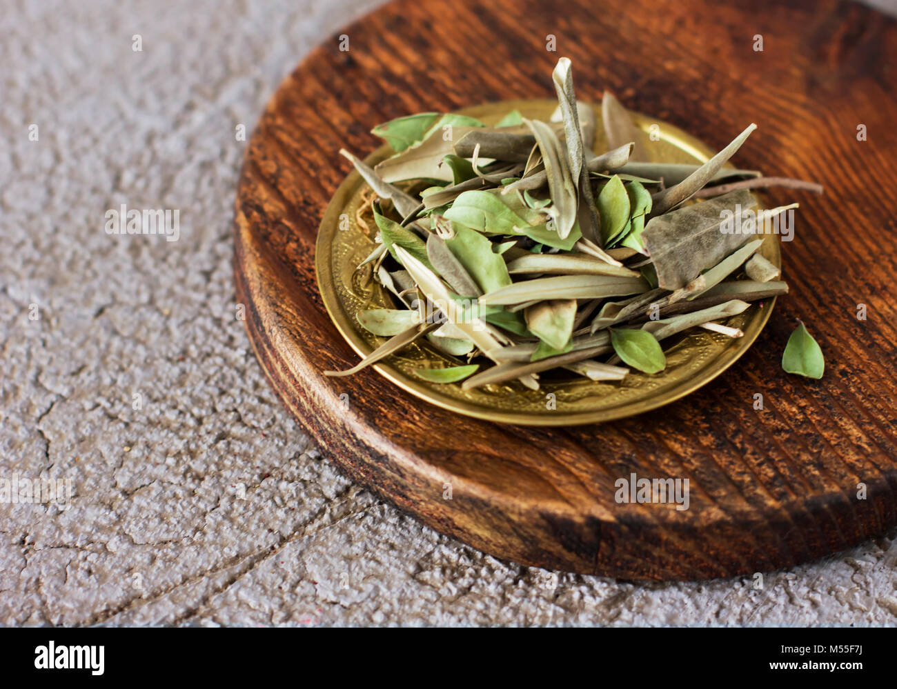 Dry olive Bay leaves in a copper plate on a wooden Board Stock Photo